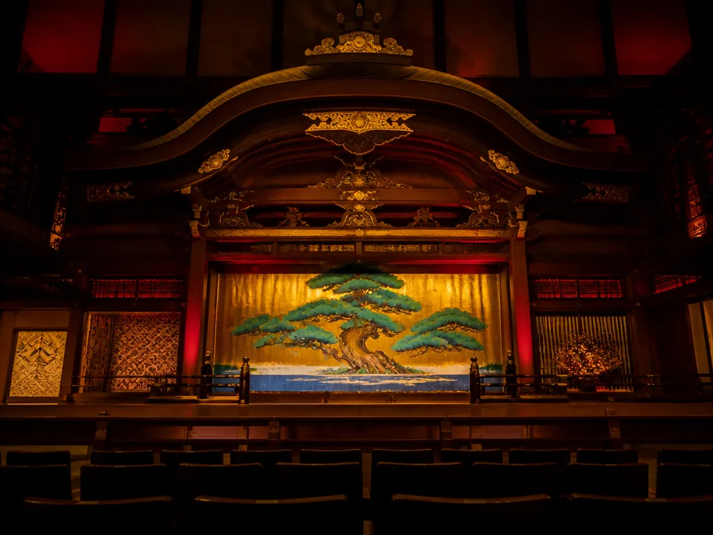 Traditionell japansk teaterscen med utsmyckad träkuliss och dramatisk röd och guldfärgad scenbelysning